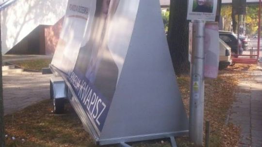 Billboard wyborczy zaparkowany na środku trawnika