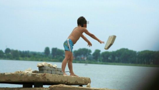 Dzieci bawią się wśród betonowych płyt i wystających drutów