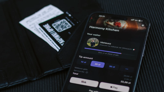 Smartfon z aplikacją GlobalTips wyświetlający profil kelnera Mateusza i opcje bezgotówkowego napiwku (10, 20, 30 zł) obok portfela z rachunkiem. Obraz ilustruje nowoczesne, bezpośrednie rozliczanie napiwków w gastronomii w kontekście wdrażania systemu KSeF.