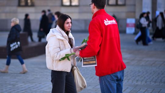 Dziennikarz dziennika wschodniego rozdający kwiaty i gazety na placu Litewskim