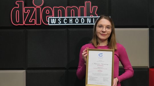 Dziennikarka z dyplomem na tle neonu Dziennika Wschodniego