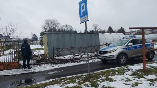 Dzielnicowy z Posterunku Policji w Werbkowicach prowadzi kobietę, która ukryła się w garażu po spowodowaniu kolizji swojego samochodu w stanie nietrzeźwości.