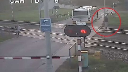 Tył autobusu na torach. Kierowca próbuje machaniem zatrzymać Pendolino