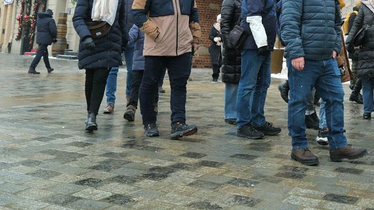 Piesi spacerujący po oblodzonym chodniku w centrum miasta zimą