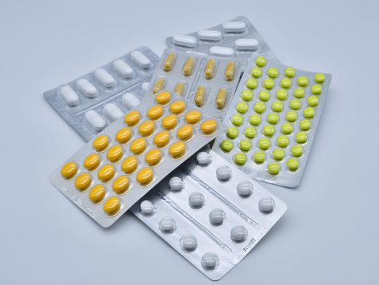 Blistry z różnymi tabletkami i kapsułkami leków na białym tle – ilustracja dotycząca farmaceutyków, leczenia i ochrony zdrowia.