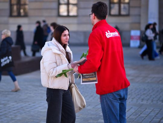 Dziennikarz dziennika wschodniego rozdający kwiaty i gazety na placu Litewskim