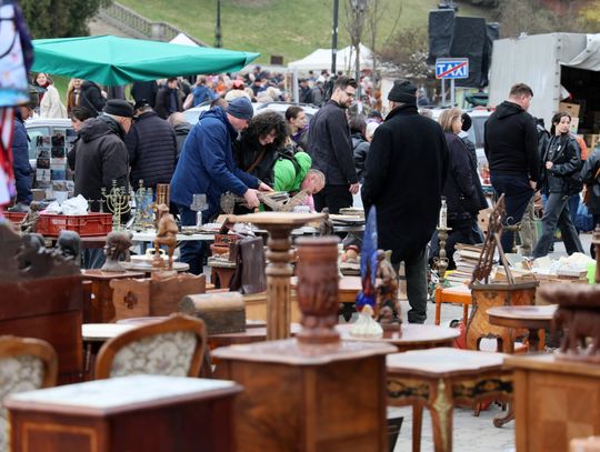 Wydmuszki, bagnety i kuchnia polowa Tłumy odwiedzających na giełdzie staroci w Lublinie przeglądają stoiska z militariami, rękodziełem i zabawkami, a w tle widać stragany z jedzeniem z kuchni polowej.