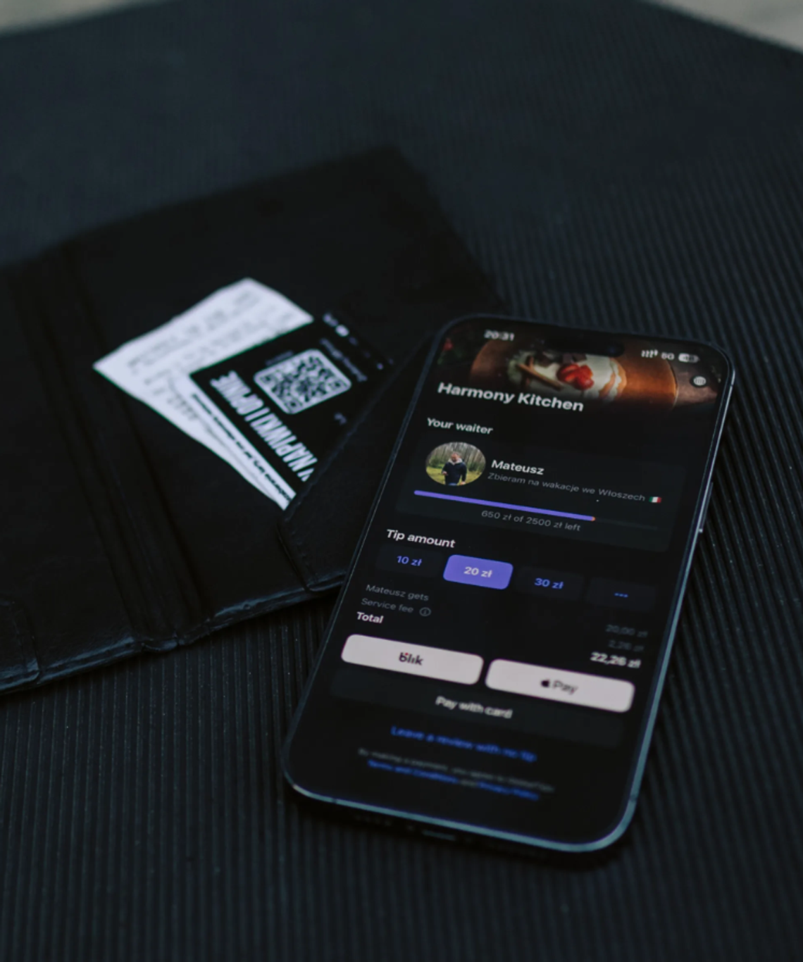 Smartfon z aplikacją GlobalTips wyświetlający profil kelnera Mateusza i opcje bezgotówkowego napiwku (10, 20, 30 zł) obok portfela z rachunkiem. Obraz ilustruje nowoczesne, bezpośrednie rozliczanie napiwków w gastronomii w kontekście wdrażania systemu KSeF.