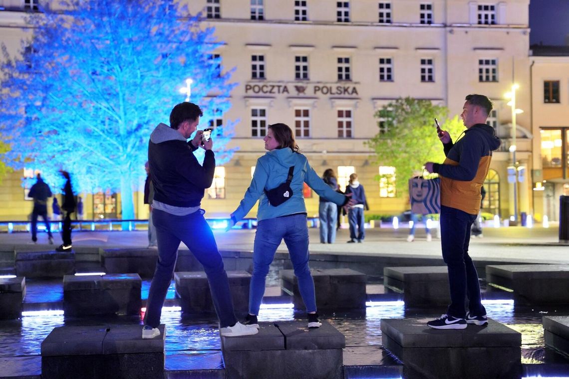 Trójka ludzi pozująca do zdjęcia przy fontannie multimedialnej w Lublinie