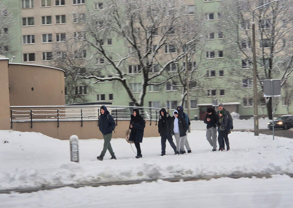 Zima w mieście – mieszkańcy poruszają się po ośnieżonym chodniku