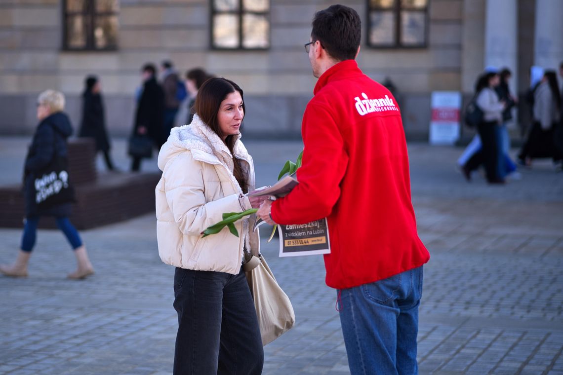 Dziennikarz dziennika wschodniego rozdający kwiaty i gazety na placu Litewskim