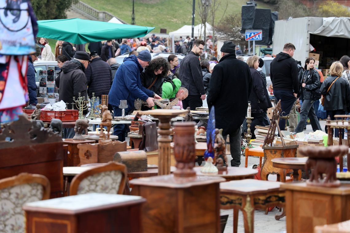 Wydmuszki, bagnety i kuchnia polowa Tłumy odwiedzających na giełdzie staroci w Lublinie przeglądają stoiska z militariami, rękodziełem i zabawkami, a w tle widać stragany z jedzeniem z kuchni polowej.