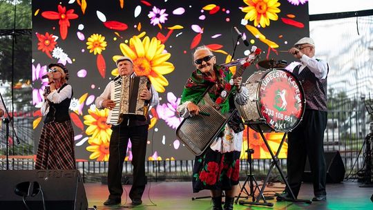 Zespół ludowy podczas występu na scenie – muzycy w tradycyjnych strojach grają koncert z akordeonem i bębnem.