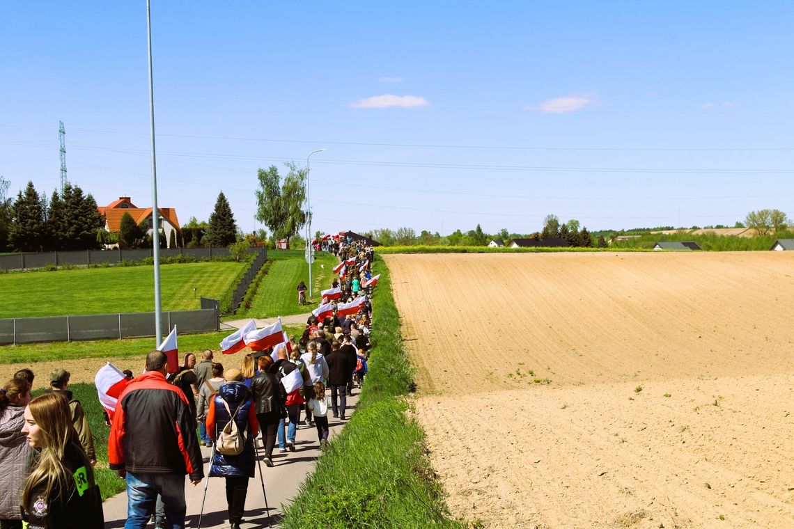 Rajd "Strzały" ku pamięci Walentego Waśkowicza Marsz z biało-czerwonymi flagami na wiejskiej drodze w woj. lubelskim – uczestnicy patriotycznego przemarszu wśród pól i zabudowań.
