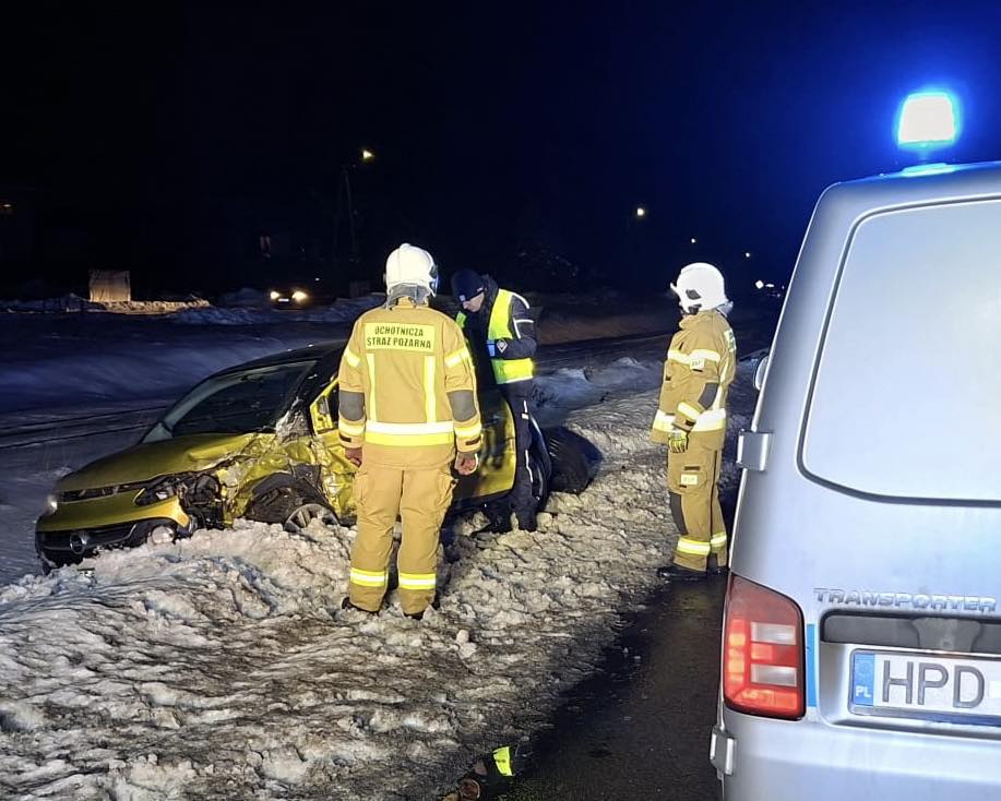 Wypadek drogowy nocą – strażacy i policja przy rozbitym samochodzie na śliskiej jezdni